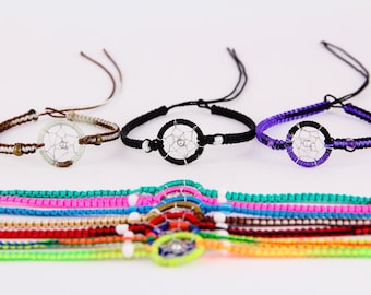 May include: A set of colorful friendship bracelets with dreamcatcher charms. The bracelets are made of woven string and feature different colors, including pink, blue, green, and yellow. The dreamcatcher charms are silver and have a delicate design.