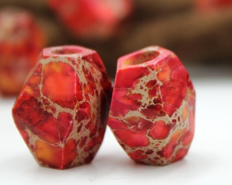 May include: Two red and orange gemstone beads with a marbled pattern. The beads are faceted and have a hole in the center for stringing.