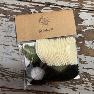 May include: A clear plastic bag containing a felt sunflower craft kit. The kit includes white felt petals, green felt leaves, and black felt for the center of the sunflower. The bag is labeled "Felt Sunflower Kit".