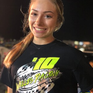 May include: A woman wearing a black t-shirt with a silver and neon green design that says "#10 Willis Racing".