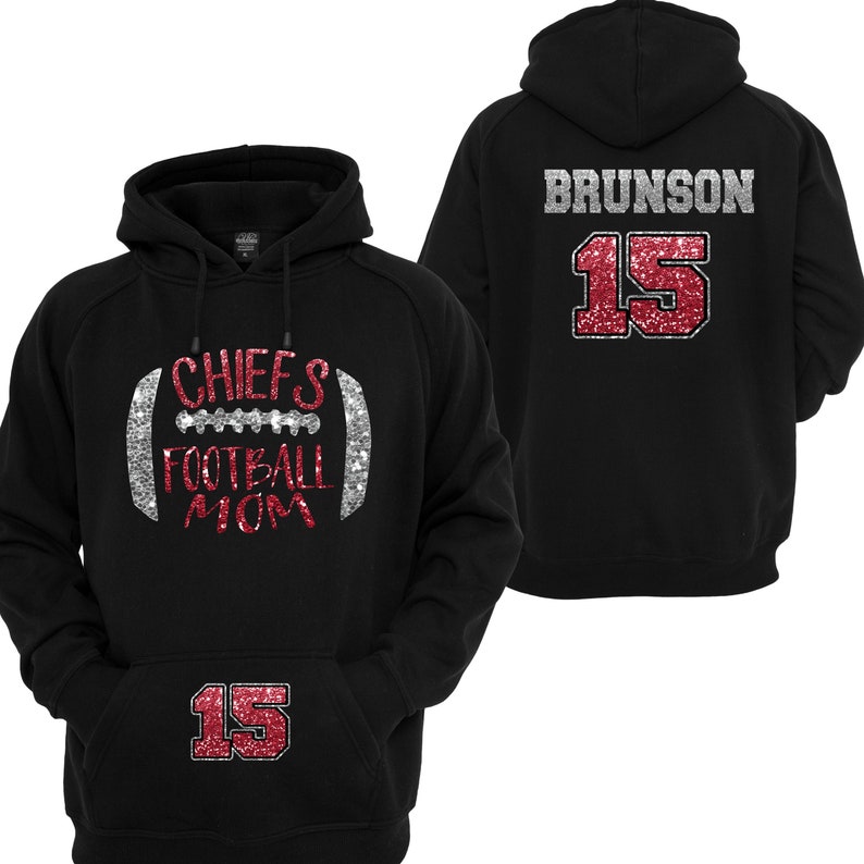 May include: Black hoodie with a red and silver glitter design. The front of the hoodie says "Chiefs Football Mom" with a football graphic. The back of the hoodie has the name "Brunson" and the number "15" in silver glitter.