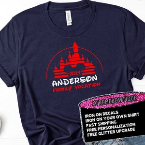 May include: Navy blue t-shirt with a red graphic of a castle and the text "2019 ANDERSON FAMILY VACATION". The shirt has rolled-up sleeves and a tag that says "CANVAS".