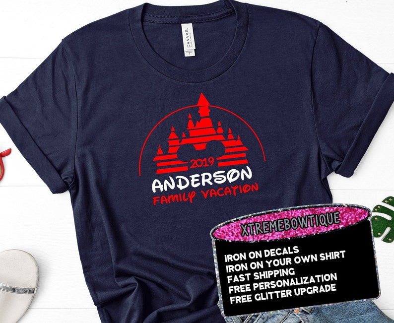 May include: Navy blue t-shirt with a red graphic of a castle and the text "2019 ANDERSON FAMILY VACATION". The shirt has rolled-up sleeves and a tag that says "CANVAS".
