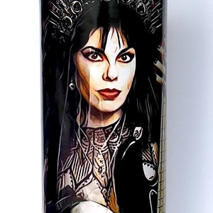 May include: A glass candle jar with a purple candle inside. The jar features a colourful image of a woman with dark hair wearing a crown and holding a skull and a guitar.