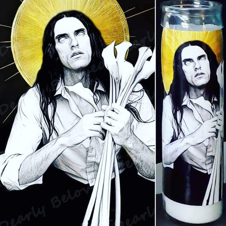 May include: A black and white illustration of a person with long hair holding a bouquet of white flowers. The person is depicted with a halo above their head. The image is printed on a white candle with a yellow background.