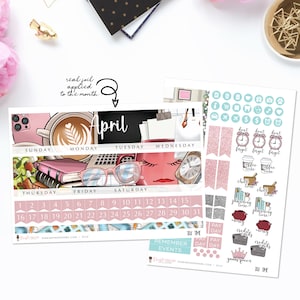 May include: A pink and white monthly planner with the word "April" in black lettering. The planner has a calendar grid with days of the week labeled. There are also several stickers with various designs, including coffee cups, clocks, and money bags.