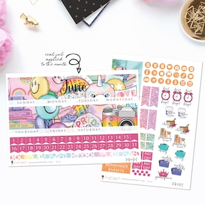May include: A June calendar planner with a unicorn, rainbow, and pride flag design. The calendar has a pink, blue, and yellow color scheme. The planner includes stickers with various designs, including coffee cups, clocks, and money bags.