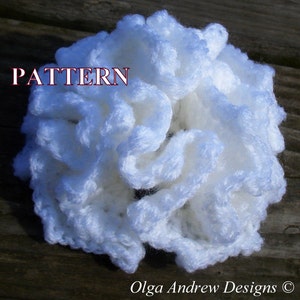 May include: White crocheted flower with a ruffled texture. The flower is made with a soft, fluffy yarn and has a delicate, feminine look.