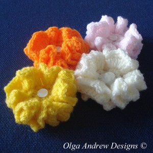 May include: Four crocheted flower embellishments in pink, white, orange, and yellow. Each flower has a white button in the center.