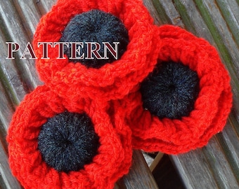 May include: Three red crocheted poppies with black centers. The poppies are arranged in a cluster on a wooden surface. The word "PATTERN" is written in white letters across the top of the image.