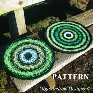 May include: Two green, white, and brown crocheted round cushions with a concentric circle pattern. The cushions are sitting on a wooden bench.