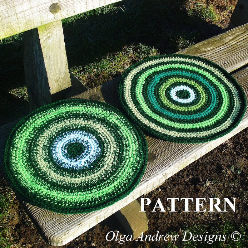 May include: Two green, white, and brown crocheted round cushions with a concentric circle pattern. The cushions are sitting on a wooden bench.