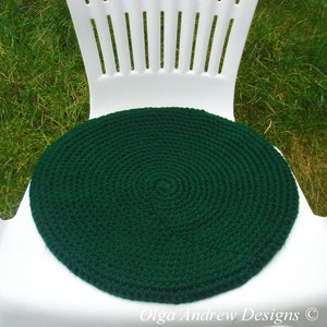 May include: A dark green crocheted round chair cushion. The cushion is made with a circular pattern and is sitting on a white chair.