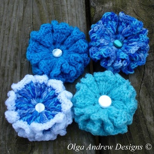 May include: Four crocheted flowers in shades of blue and white. Each flower has a white button in the center.