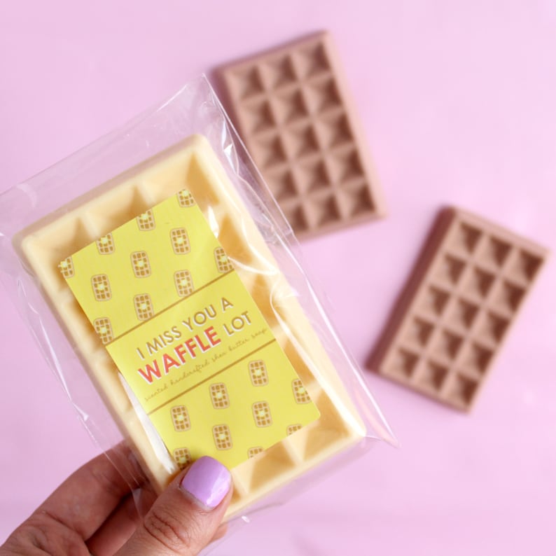 May include: A white waffle-shaped soap bar with a yellow label that reads "I miss you a waffle lot" and a waffle pattern. The soap is in a clear plastic bag.