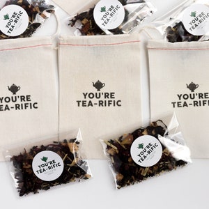 May include: Three white cotton drawstring bags with the text "You're Tea-Rific" printed on them. Each bag contains a small clear plastic bag filled with loose leaf tea.