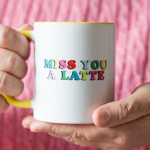 May include: White ceramic mug with a yellow rim, featuring the text "Miss You A Latte" in colorful letters.