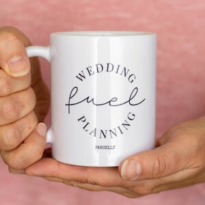 May include: White ceramic mug with black text that reads "Wedding Fuel Planning" in a circle. The text "Parchelly" is printed below the circle.