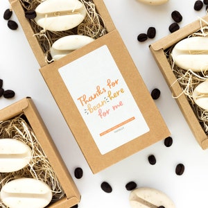 May include: A set of three brown boxes filled with coffee bean shaped soaps. Each box has a label that says "Thanks for bean-ing here for me".