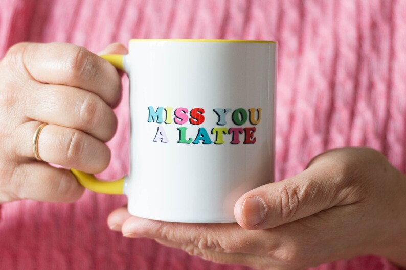 May include: White ceramic mug with a yellow rim, featuring the text "Miss You A Latte" in colorful letters.