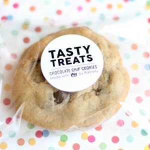 May include: A single chocolate chip cookie in a clear plastic bag with a white circle sticker that says "Tasty Treats Chocolate Chip Cookies Made with LOVE by Parcelly"