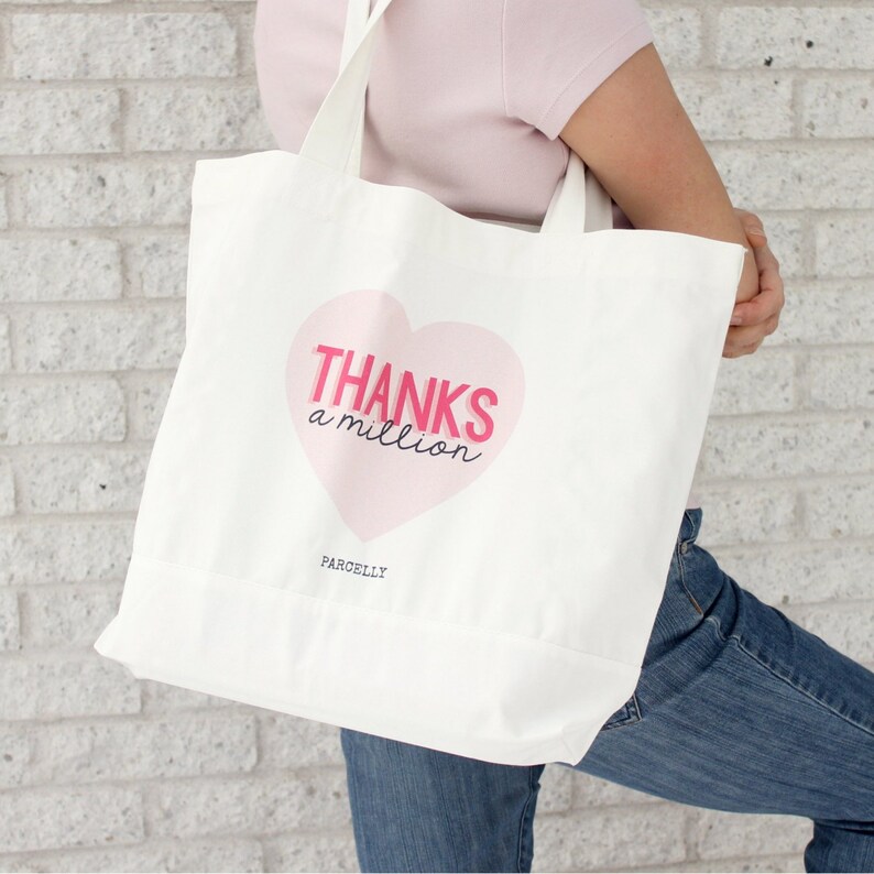 May include: White canvas tote bag with a pink heart design. The heart has the text "THANKS a million" in pink lettering. The bag has the word "PARCELLY" printed on the bottom.