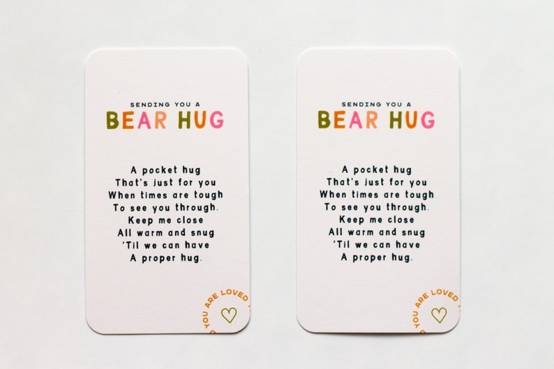 May include: Two white cards with colourful text that reads "Sending you a Bear Hug". The cards have a poem about a hug and a heart with the text "You are Loved" in a circle.