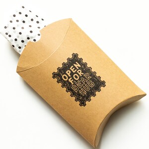 May include: A brown cardboard gift box with white polka dot tissue paper inside. The box has a black and white stamp that says "Open for Bear Hug".