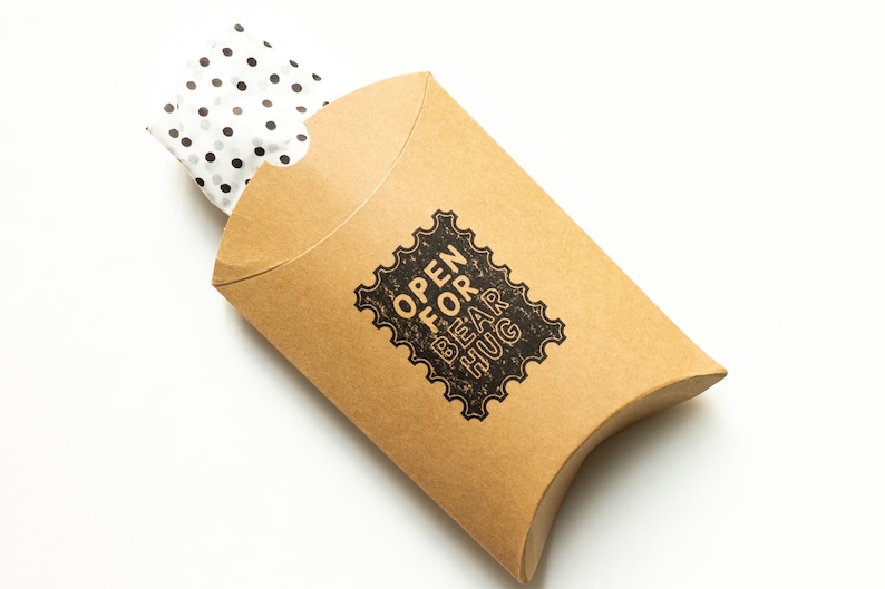 May include: A brown cardboard gift box with white polka dot tissue paper inside. The box has a black and white stamp that says "Open for Bear Hug".
