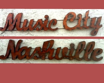 May include: Rusty metal signs that read "Music City" and "Nashville" in a cursive font. The signs are mounted on a light-colored wooden surface. The top of the image reads "NEW STYLES" and "GOOD SIZE TO PUT ANY WHERE YOU WOULD LIKE".