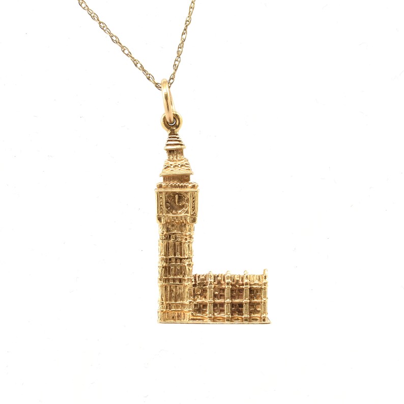 May include: A gold necklace with a pendant shaped like Big Ben, the famous clock tower in London.