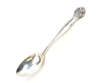 May include: A silver spoon with an ornate handle. The handle has a floral design.
