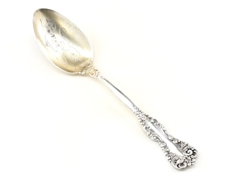 May include: A silver spoon with an ornate handle and a decorative design on the bowl. The spoon is made of sterling silver and has a polished finish.