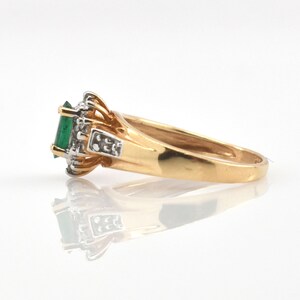 May include: A gold ring featuring a central rectangular green gemstone set in a white metal prong setting. The band is polished yellow gold, and the setting is accented with small clear stones on the sides, creating a multi-toned metal appearance.
