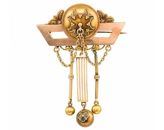 May include: Antique gold-tone brooch with intricate details. The brooch features a central circular design with ornate patterns, a geometric frame, and dangling chains with spherical and floral accents. A classic piece of jewelry.