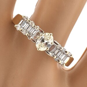 May include: A gold and silver ring featuring two oval-cut diamonds and several baguette-cut diamonds. The ring has a classic design with a central focus on the two larger stones.