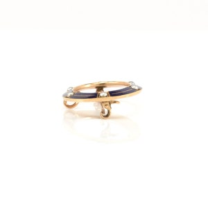 May include: A gold ring with a blue enamel design and pearl accents. The ring is on a white background.