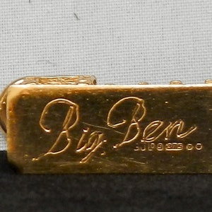May include: Gold-colored metal charm with the inscription "Big Ben" and the date "July 9, 1993" engraved on the front.