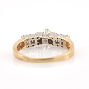May include: A gold and silver ring with a central diamond and smaller accent stones. The ring has a classic design with a gold band and a silver setting for the diamonds. The ring is set against a white background.