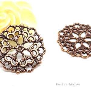 May include: Two copper-colored metal filigree embellishments with a circular design. The embellishments have a delicate, intricate pattern with a floral motif.