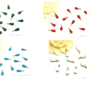 Op de afbeelding: Assortiment van kleurrijke traanvormige bedels met gouden springringen. De bedels zijn groen, rood, turquoise en wit.