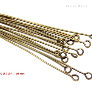 Può includere: Un mazzo di spilli per la testa dorati lunghi 60 mm con un anello all'estremità. LONGUEUR: 60 mm