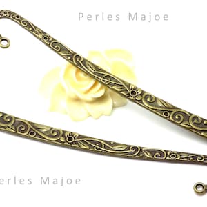 Peut inclure: Deux marque-pages en bronze orné avec des motifs floraux. Le marque-page a un crochet à une extrémité et un motif floral décoratif sur toute la longueur. Le texte "Perles Majoe" est visible sur l'image.