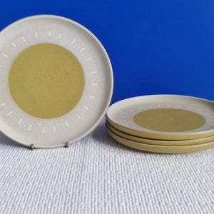 May include: Set of four white ceramic dinner plates with a yellow centre circle and a white geometric pattern around the edge.