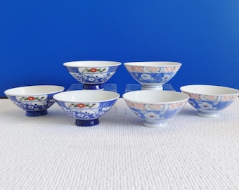 Könnte beinhalten: Sechs kleine, weiße Keramikschalen mit blauen und floralen Mustern. Die Schalen haben eine abgerundete Form und einen kleinen Fuß.