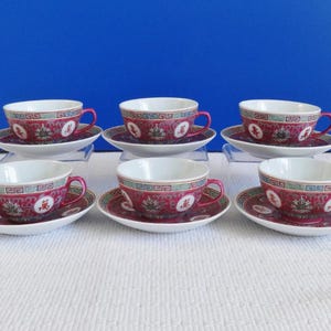 May include: Set of six red and white teacups and saucers with a traditional Chinese design. The cups and saucers have a gold trim.