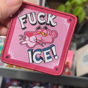 Puede incluir: Parche bordado rosa con el texto "FUCK ICE!" y un personaje de dibujos animados de la Pantera Rosa fumando un cigarrillo. El parche tiene un fondo rosa, un borde rosa oscuro y texto blanco.