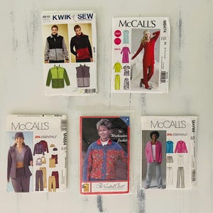 May include: Five sewing pattern envelopes featuring various clothing designs. The collection includes Kwik Sew 3815, McCall's M6474, M4664, M4789, and a Quilted Visit pattern. Each envelope displays illustrations of finished garments like jackets, pants, and tops.