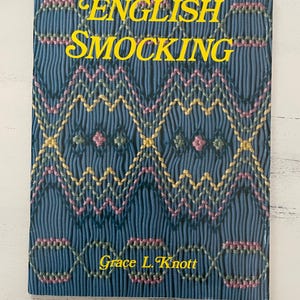 May include: A book titled "English Smocking" by Grace L. Knott. The cover features a blue fabric with a colorful smocking pattern in pink, yellow, and green.