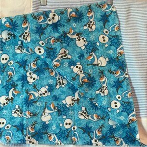 May include: A blue fleece baby blanket with a repeating pattern of Olaf from Frozen. The blanket is made of soft, plush fabric and is perfect for cuddling.